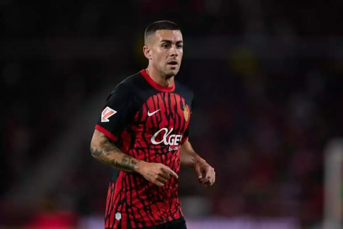 Futbolista con uniforme negro y rojo en medio de un partido