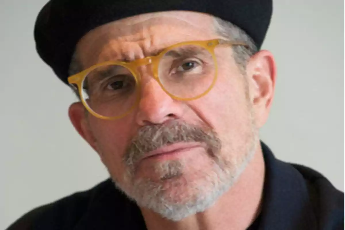 Hombre de barba canosa con gafas de montura amarilla y boina negra mirando a la cámara Hombre de barba canosa con gafas de montura amarilla y boina negra mirando a la cámara