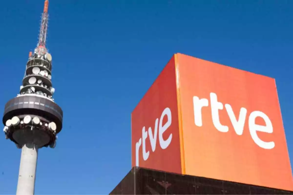 Edificio de RTVE junto a una torre de telecomunicaciones bajo un cielo azul Edificio de RTVE junto a una torre de telecomunicaciones bajo un cielo azul