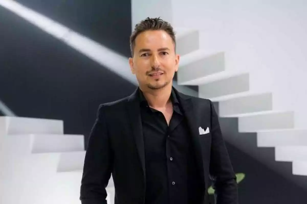 Hombre de cabello corto y barba recortada vistiendo traje negro con fondo de escaleras blancas y paredes modernas Hombre de cabello corto y barba recortada vistiendo traje negro con fondo de escaleras blancas y paredes modernas