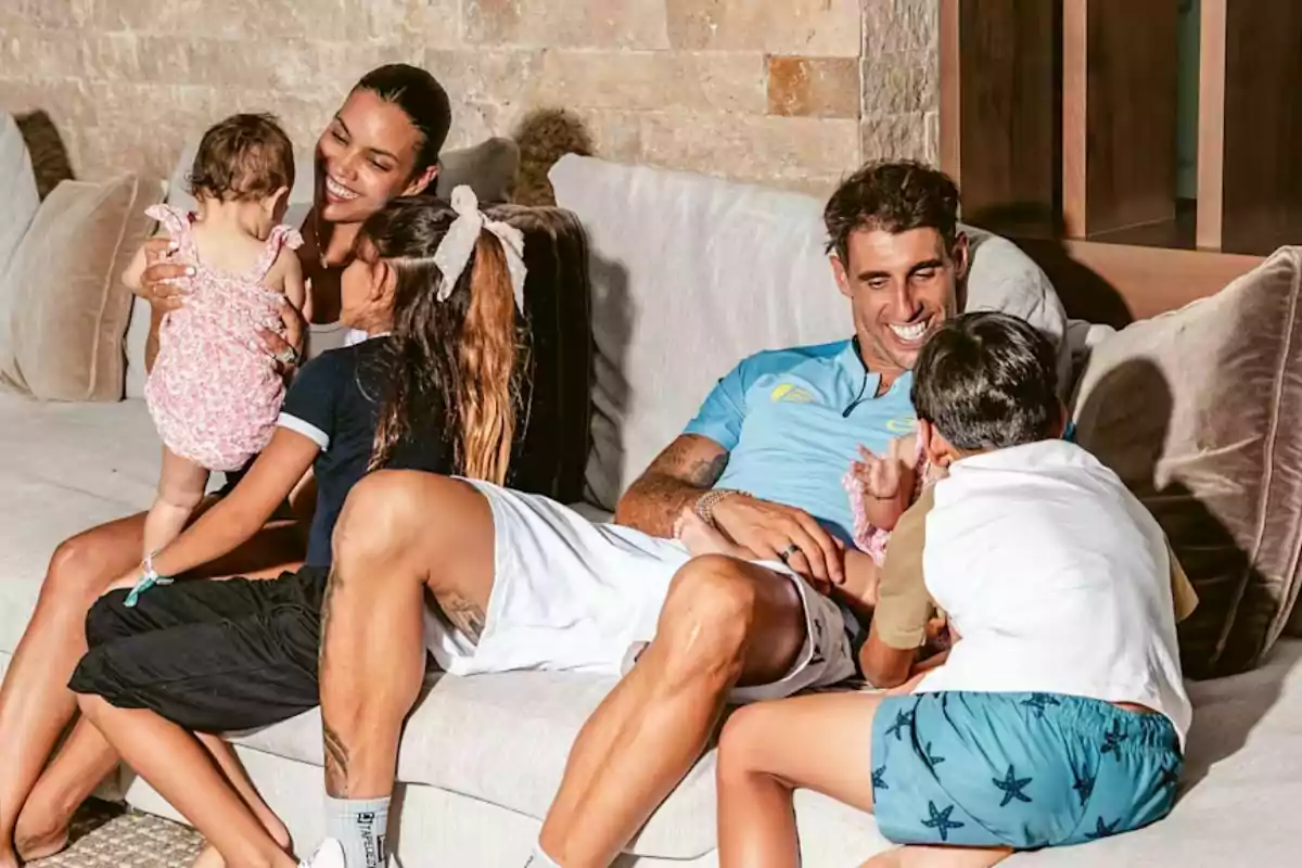 Familia sentada en un sofá disfrutando de un momento alegre juntos mientras sonríen y juegan Familia sentada en un sofá disfrutando de un momento alegre juntos mientras sonríen y juegan