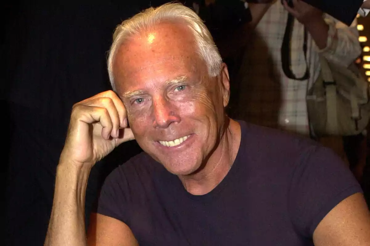 Hombre de cabello canoso y piel bronceada sonriendo y apoyando la cabeza en su mano Hombre de cabello canoso y piel bronceada sonriendo y apoyando la cabeza en su mano