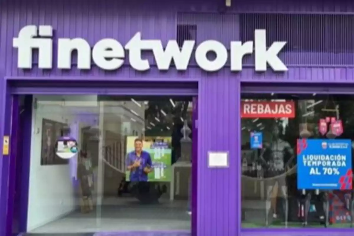 Fachada de una tienda Finetwork con paredes moradas y letrero grande, anuncios de rebajas y liquidación en el escaparate Fachada de una tienda Finetwork con paredes moradas y letrero grande, anuncios de rebajas y liquidación en el escaparate