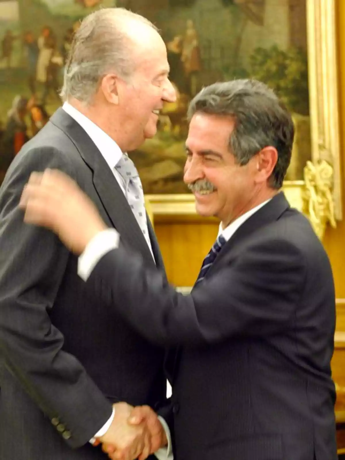 Dos hombres de traje se saludan sonrientes en un ambiente formal con un cuadro al fondo Dos hombres de traje se saludan sonrientes en un ambiente formal con un cuadro al fondo