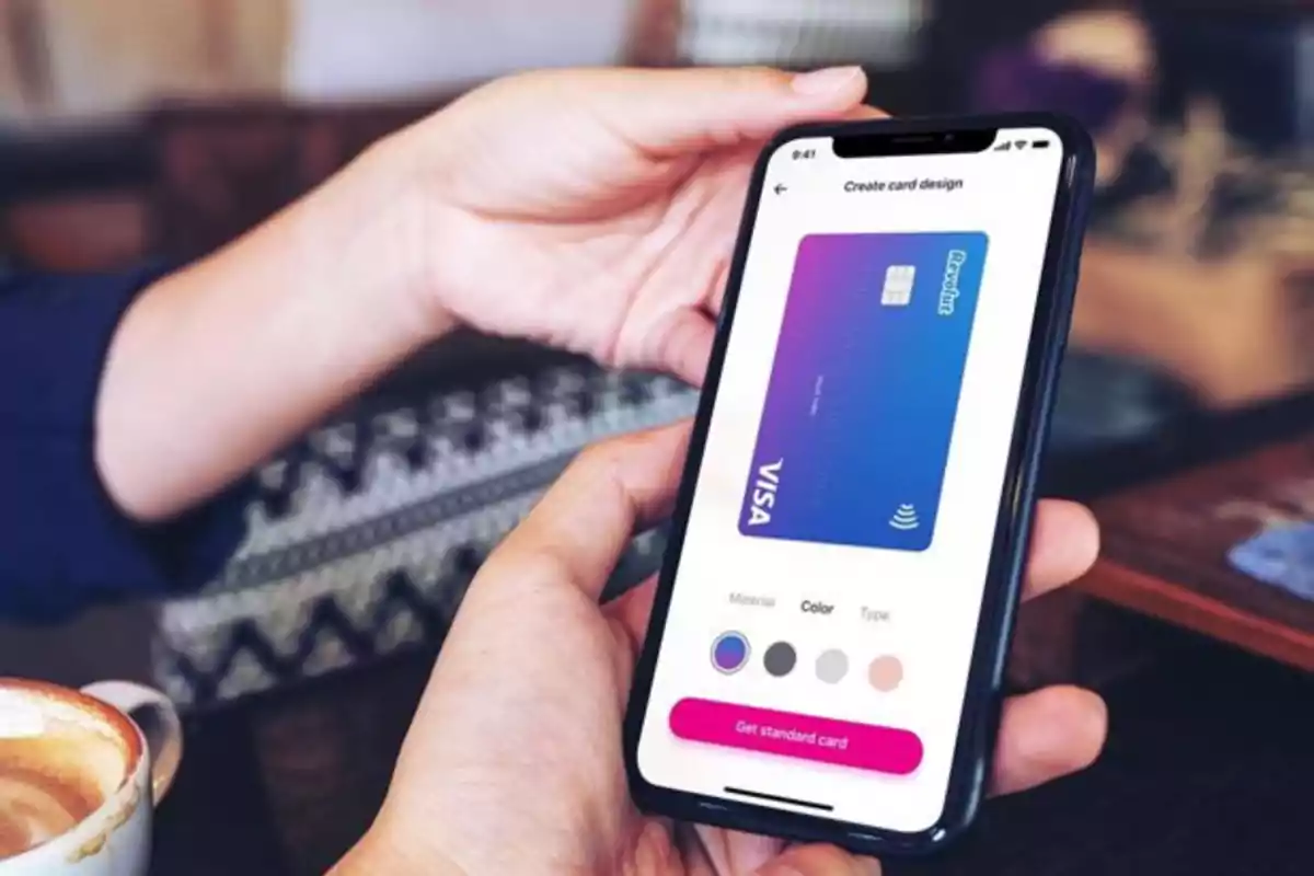 Persona sosteniendo un teléfono móvil que muestra en pantalla el diseño de una tarjeta bancaria Visa mientras está sentada en una cafetería Persona sosteniendo un teléfono móvil que muestra en pantalla el diseño de una tarjeta bancaria Visa mientras está sentada en una cafetería