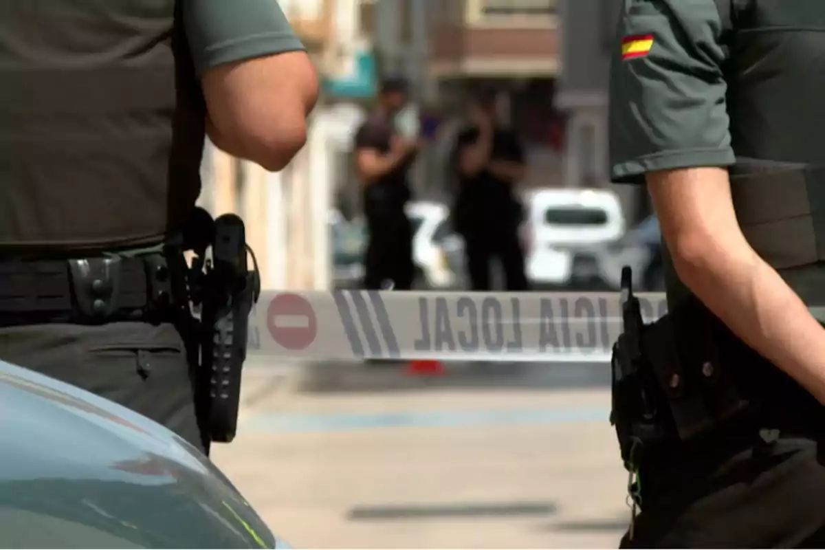 Agentes de policía custodian una zona acordonada en una calle urbana Agentes de policía custodian una zona acordonada en una calle urbana
