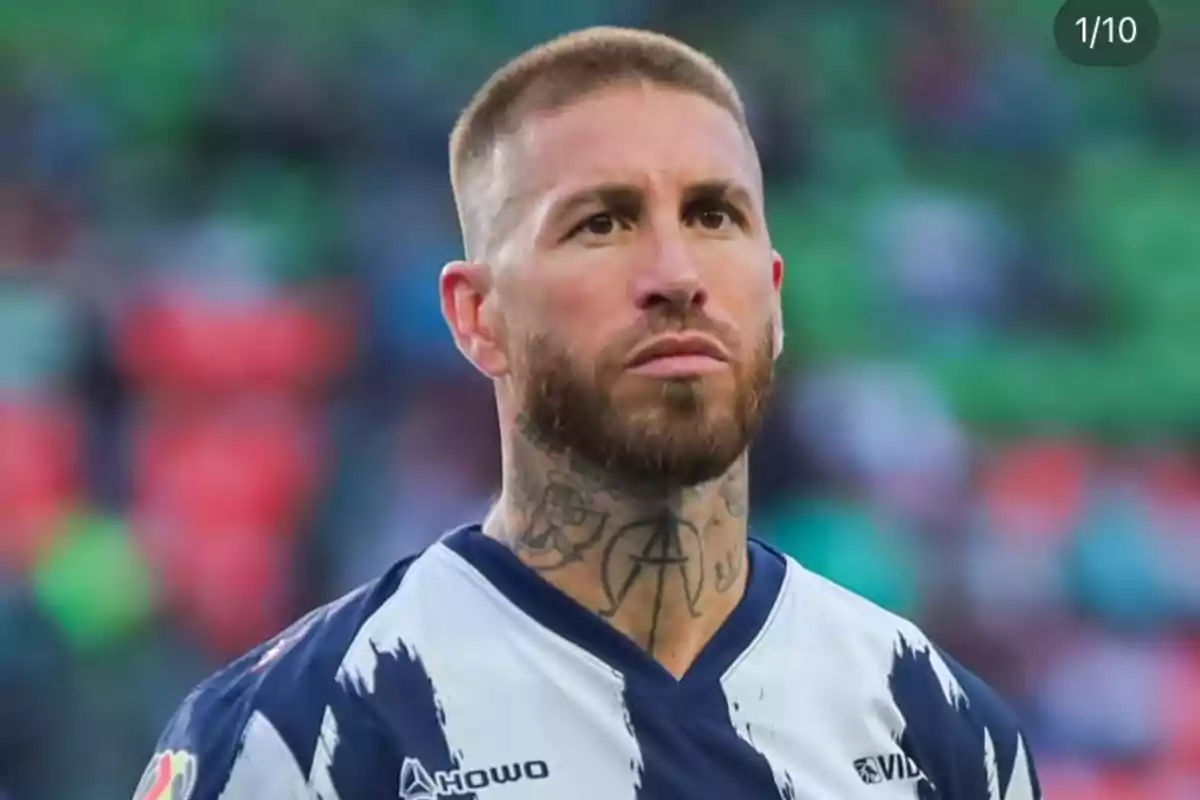 Futbolista con barba y tatuajes en el cuello vistiendo un uniforme azul y blanco en un estadio Futbolista con barba y tatuajes en el cuello vistiendo un uniforme azul y blanco en un estadio