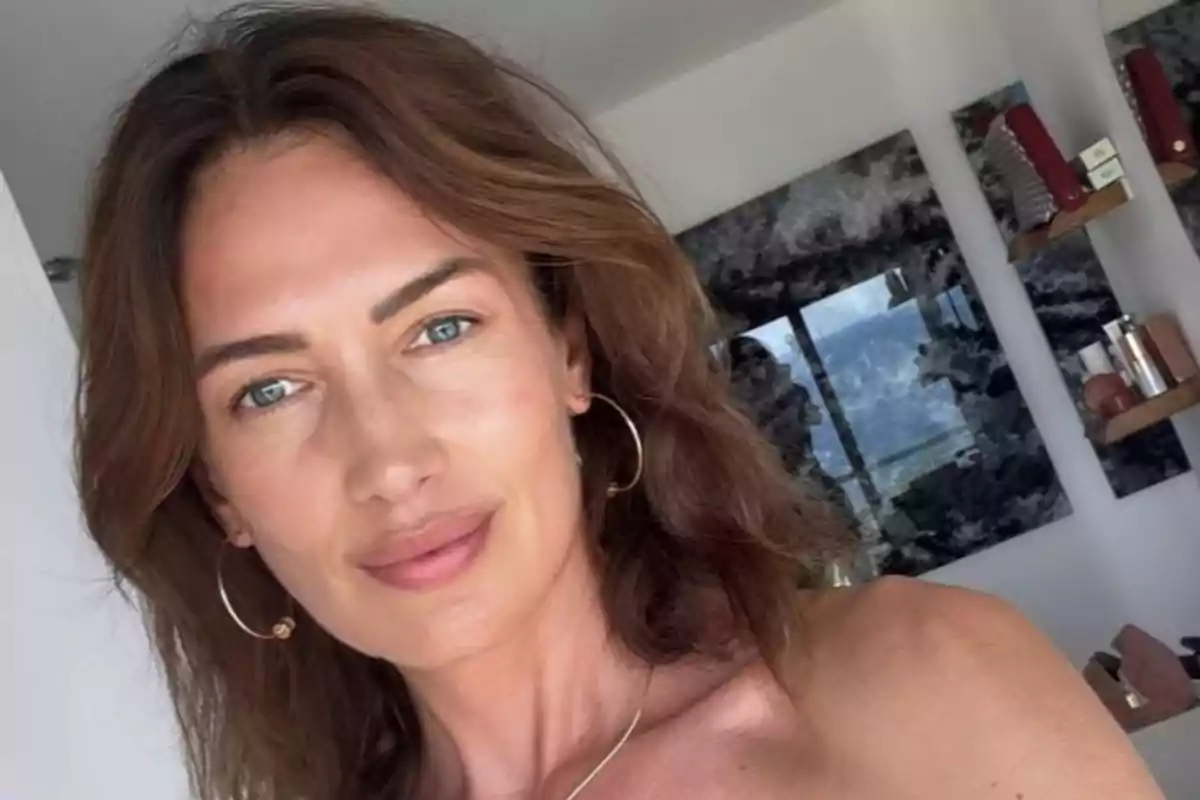 Mujer de cabello castaño y ojos claros posando en una habitación moderna con estantes y espejos al fondo Mujer de cabello castaño y ojos claros posando en una habitación moderna con estantes y espejos al fondo