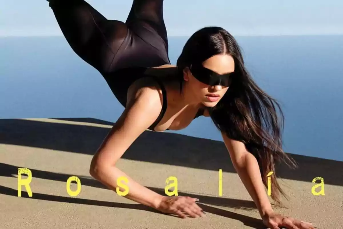 Mujer con gafas oscuras y ropa negra en una pose dinámica sobre una superficie beige con el mar de fondo y el texto Rosalía en amarillo Mujer con gafas oscuras y ropa negra en una pose dinámica sobre una superficie beige con el mar de fondo y el texto Rosalía en amarillo