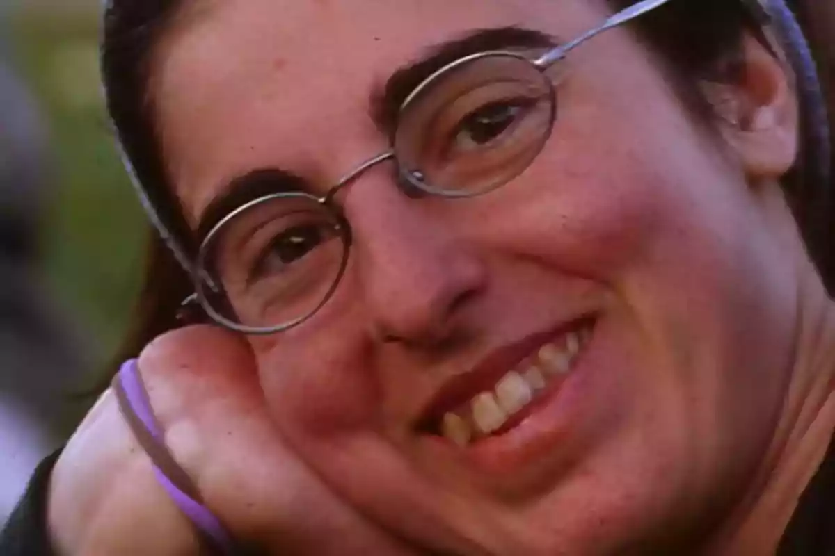 Persona con gafas sonriendo y apoyando la cabeza en su mano Persona con gafas sonriendo y apoyando la cabeza en su mano