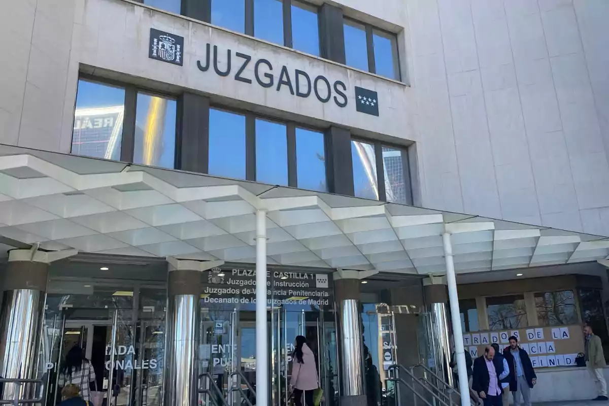 Fachada de un edificio de juzgados con varias personas entrando y saliendo por la puerta principal Fachada de un edificio de juzgados con varias personas entrando y saliendo por la puerta principal