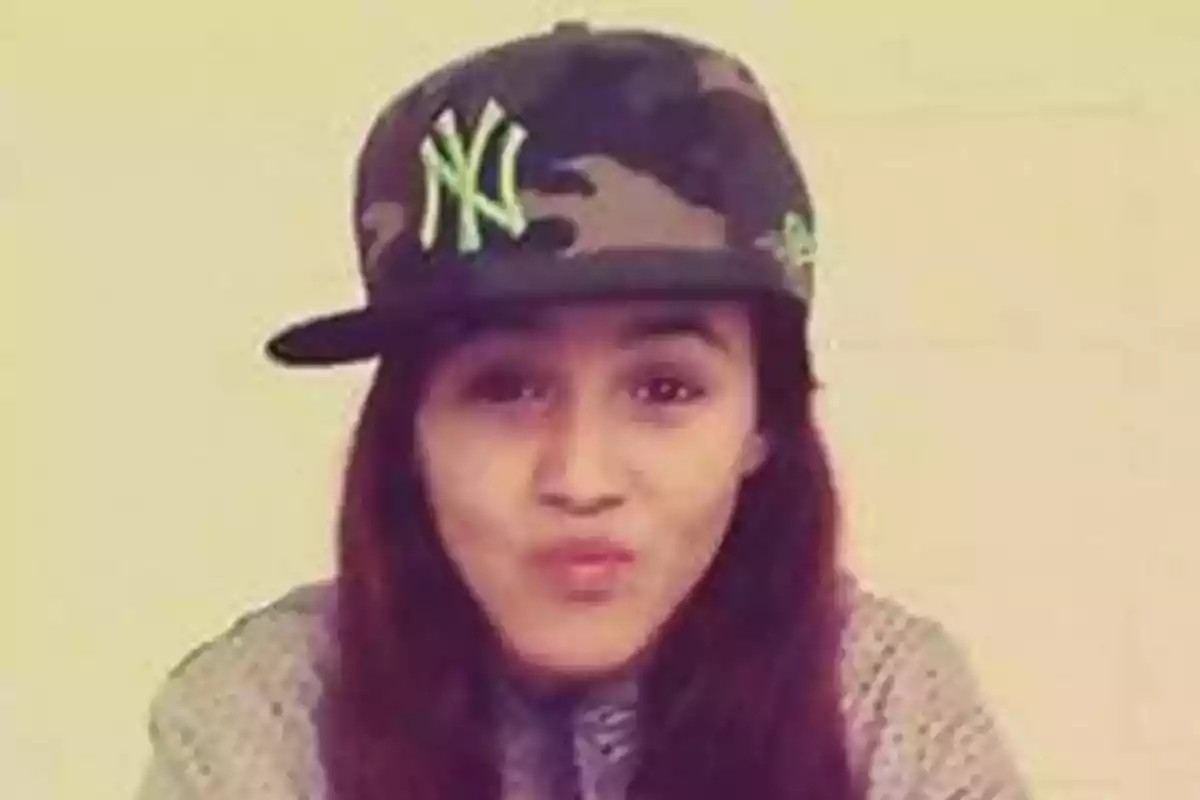 Joven con gorra de camuflaje y logotipo verde haciendo un gesto divertido frente a la cámara Joven con gorra de camuflaje y logotipo verde haciendo un gesto divertido frente a la cámara
