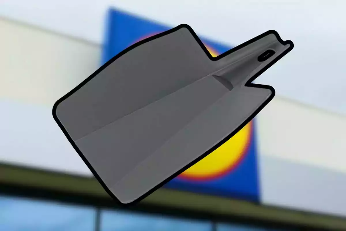 Pala de plástico gris con borde negro sostenida frente a un edificio con un cartel desenfocado de colores azul, amarillo y rojo Pala de plástico gris con borde negro sostenida frente a un edificio con un cartel desenfocado de colores azul, amarillo y rojo