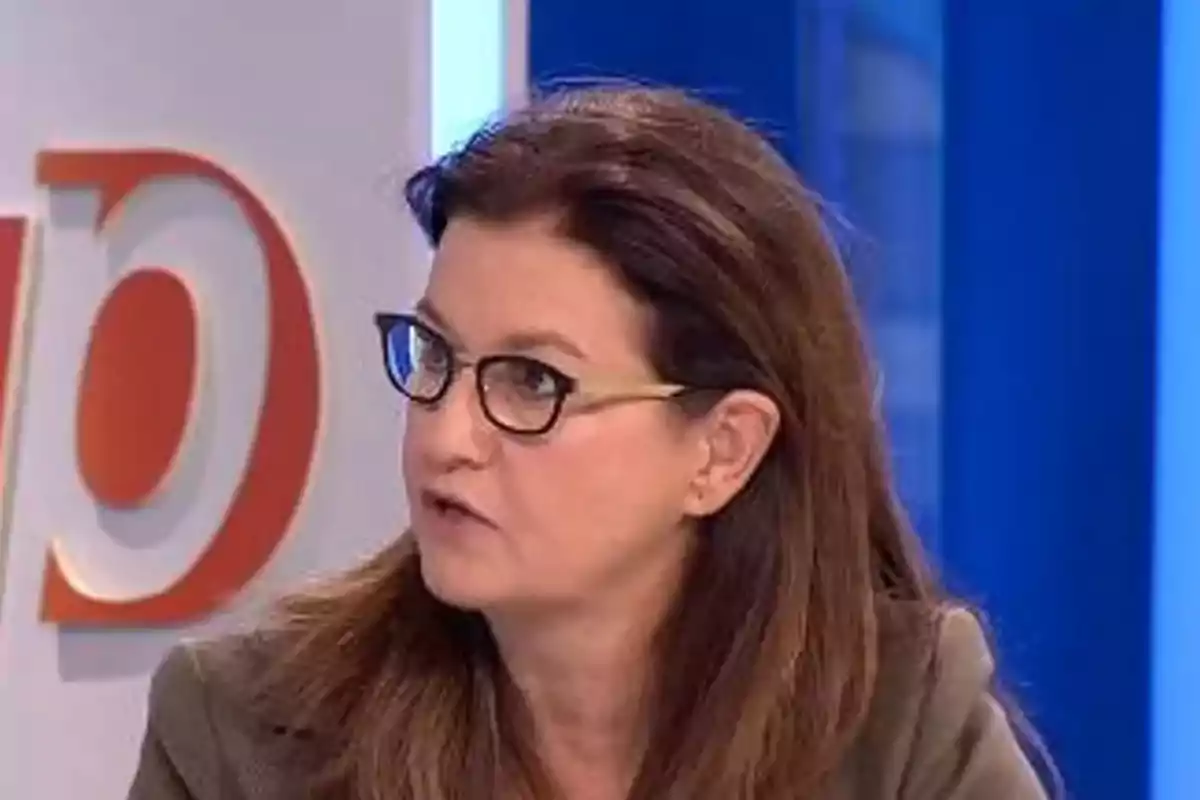 Mujer de cabello castaño y gafas hablando en un estudio de televisión Mujer de cabello castaño y gafas hablando en un estudio de televisión