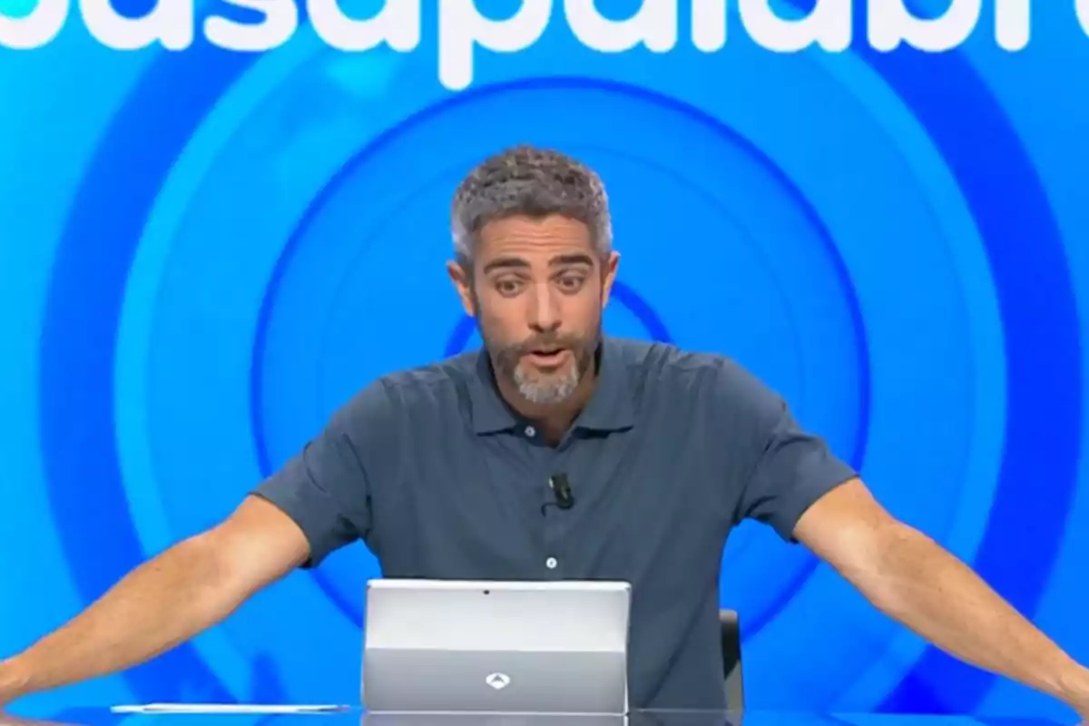 Roberto Leal sentado frente a una tablet en un set de televisión con fondo azul y letras blancas. Captura de 'Pasapalabra' Roberto Leal sentado frente a una tablet en un set de televisión con fondo azul y letras blancas. Captura de 'Pasapalabra'