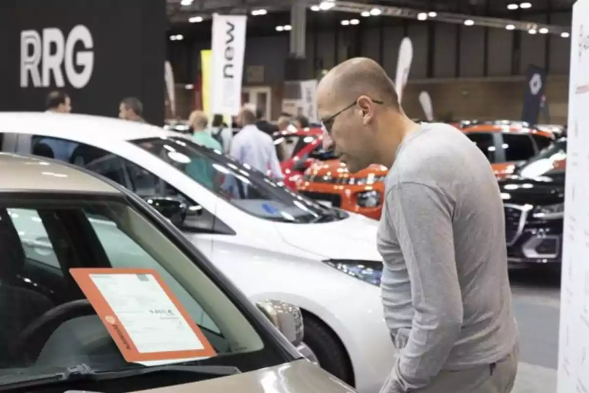 Hombre observando la información de un coche en una exposición de autos Hombre observando la información de un coche en una exposición de autos