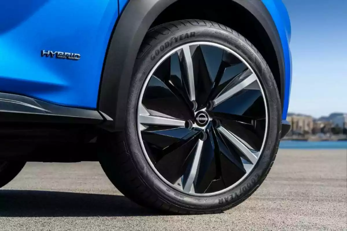 Llanta de automóvil Nissan con rines deportivos y carrocería azul estacionado al aire libre Llanta de automóvil Nissan con rines deportivos y carrocería azul estacionado al aire libre