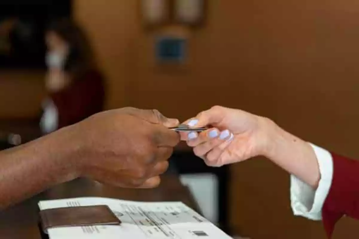 Dos personas intercambian una tarjeta en la recepción de un hotel