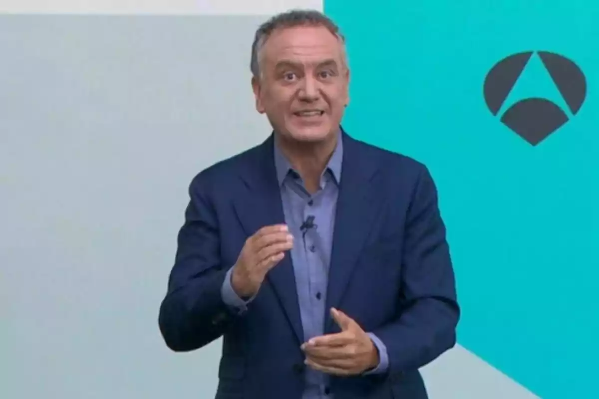 Plano medio de Roberto Brasero hablando frente a una pared de fondo azul claro con un logotipo geométrico oscuro a la derecha. Plano medio de Roberto Brasero hablando frente a una pared de fondo azul claro con un logotipo geométrico oscuro a la derecha.