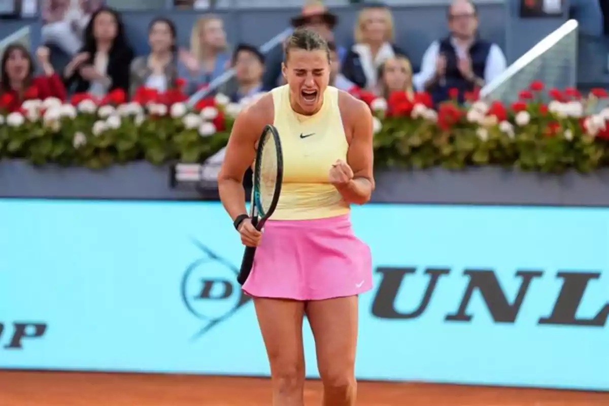 Tenista celebrando con emoción en una cancha de arcilla durante un partido, vistiendo camiseta amarilla y falda rosa, con público de fondo. Tenista celebrando con emoción en una cancha de arcilla durante un partido, vistiendo camiseta amarilla y falda rosa, con público de fondo.