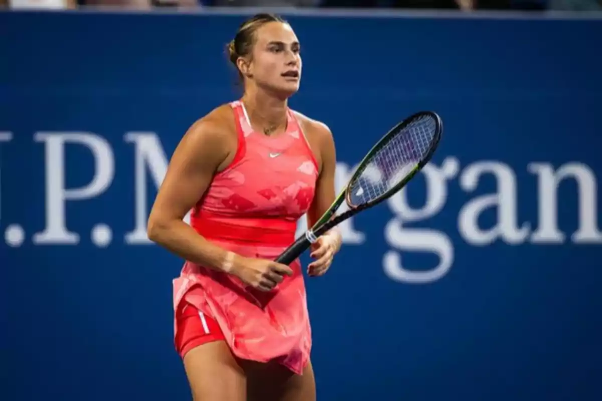 Tenista con vestido rosa sosteniendo una raqueta durante un partido en una cancha profesional Tenista con vestido rosa sosteniendo una raqueta durante un partido en una cancha profesional