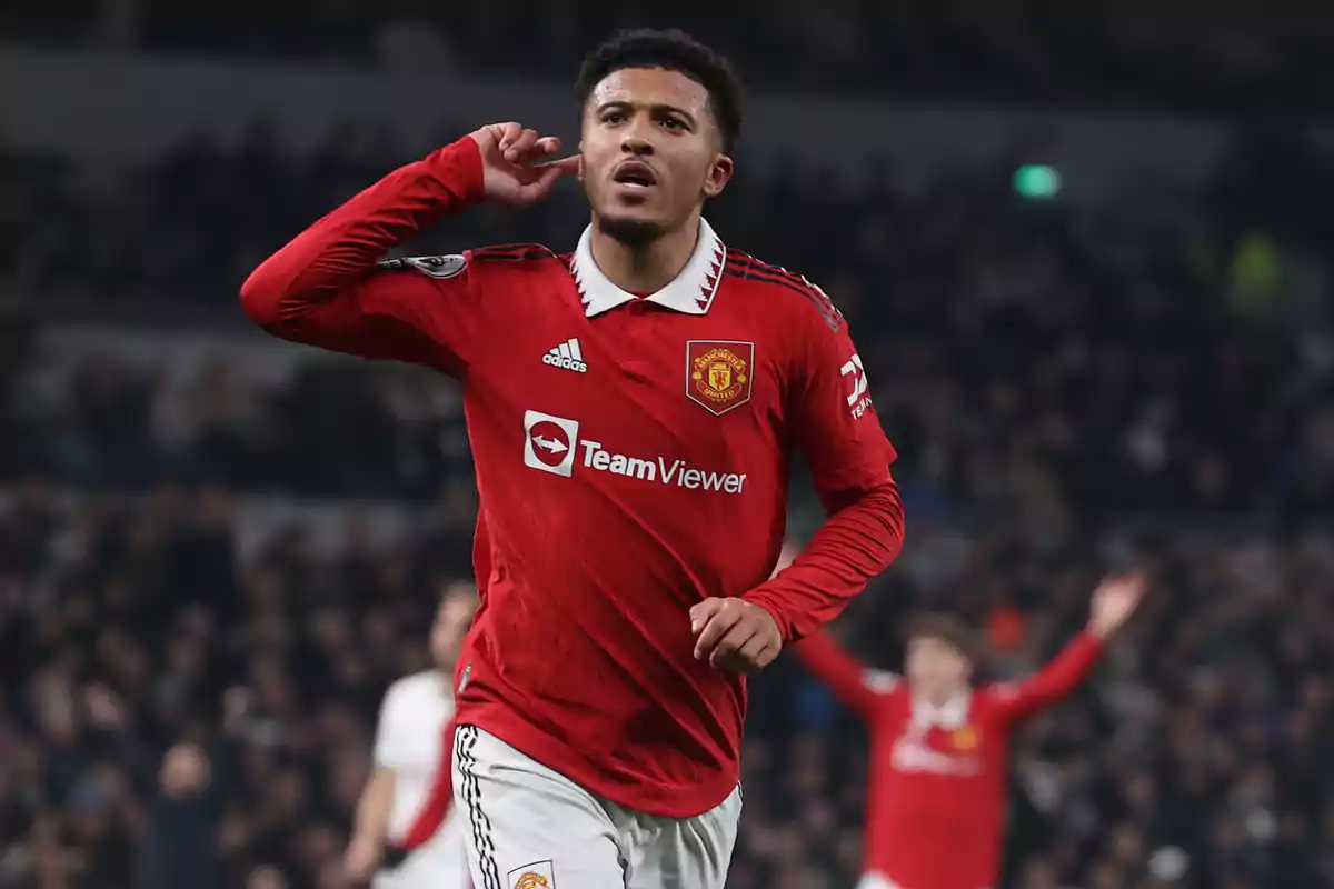 Futbolista del Manchester United celebrando un gol en el estadio con la mano en la oreja y el público de fondo Futbolista del Manchester United celebrando un gol en el estadio con la mano en la oreja y el público de fondo