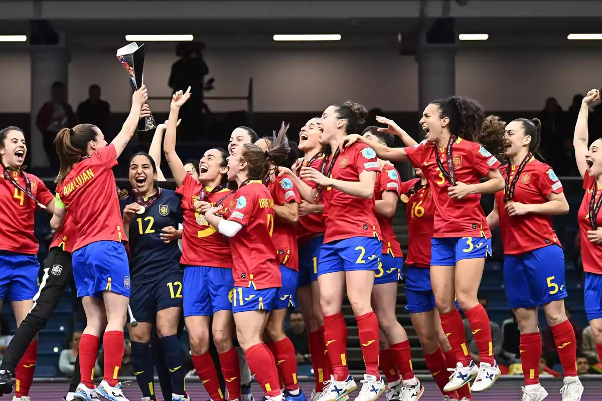 Jugadoras de un equipo femenino de fútbol celebran con entusiasmo levantando un trofeo en el podio Jugadoras de un equipo femenino de fútbol celebran con entusiasmo levantando un trofeo en el podio