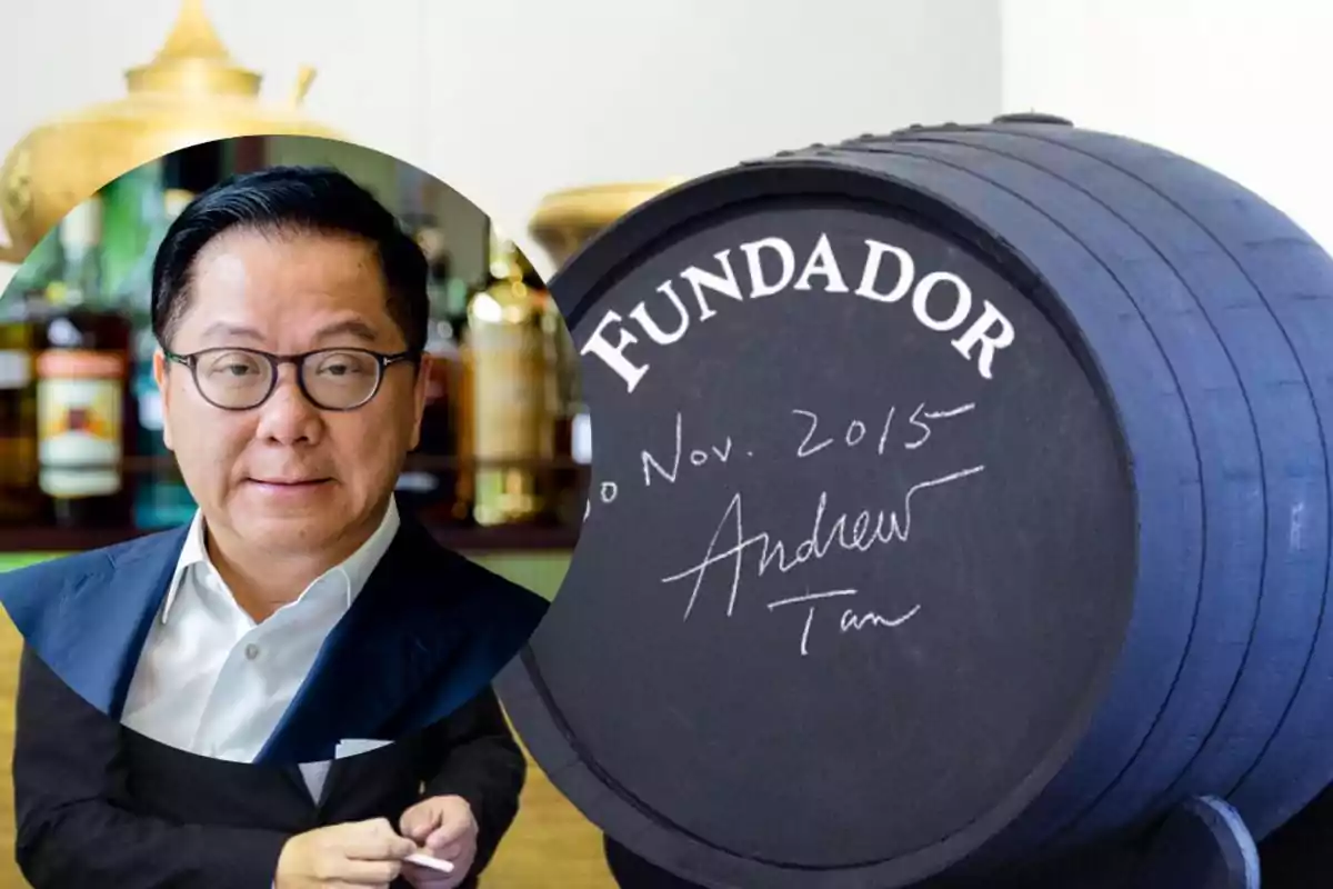 Hombre con gafas y traje oscuro en primer plano y un barril de madera con la palabra Fundador y una firma en el fondo Hombre con gafas y traje oscuro en primer plano y un barril de madera con la palabra Fundador y una firma en el fondo