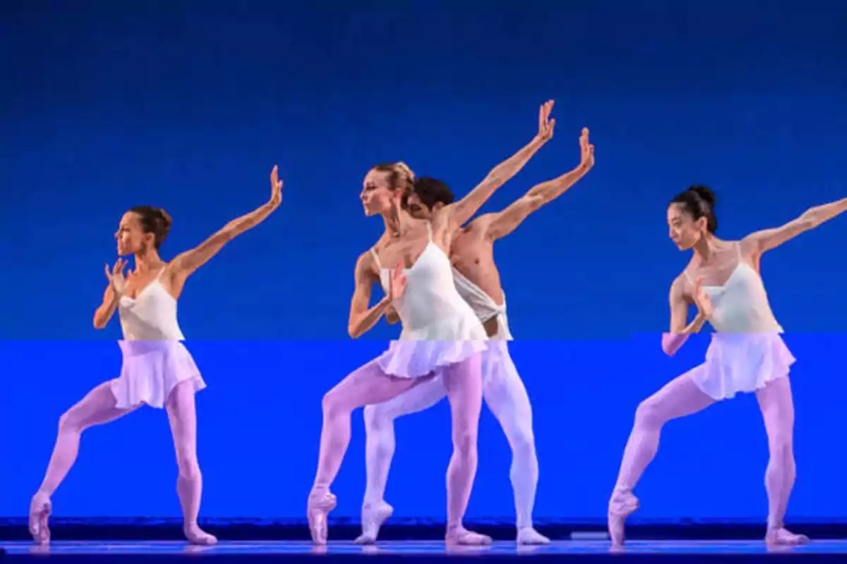 Bailarines de ballet en el escenario con trajes blancos realizando una coreografía sincronizada.