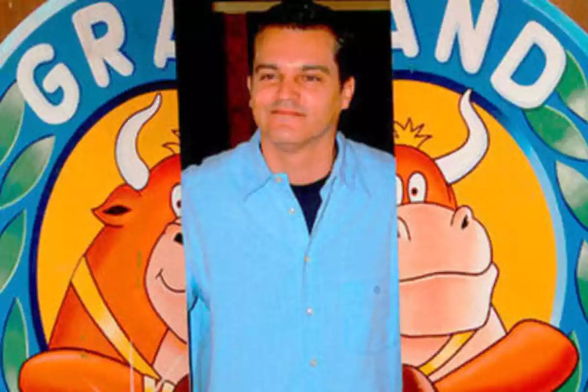 Hombre con camisa azul frente a un cartel de dibujos animados de toros sonrientes.