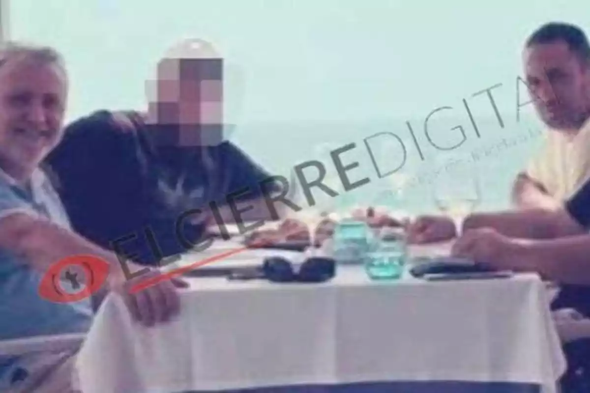 Tres personas sentadas alrededor de una mesa en un restaurante con vista al mar, una de ellas con el rostro pixelado y la marca de agua "EL CIERRE DIGITAL" sobre la imagen.