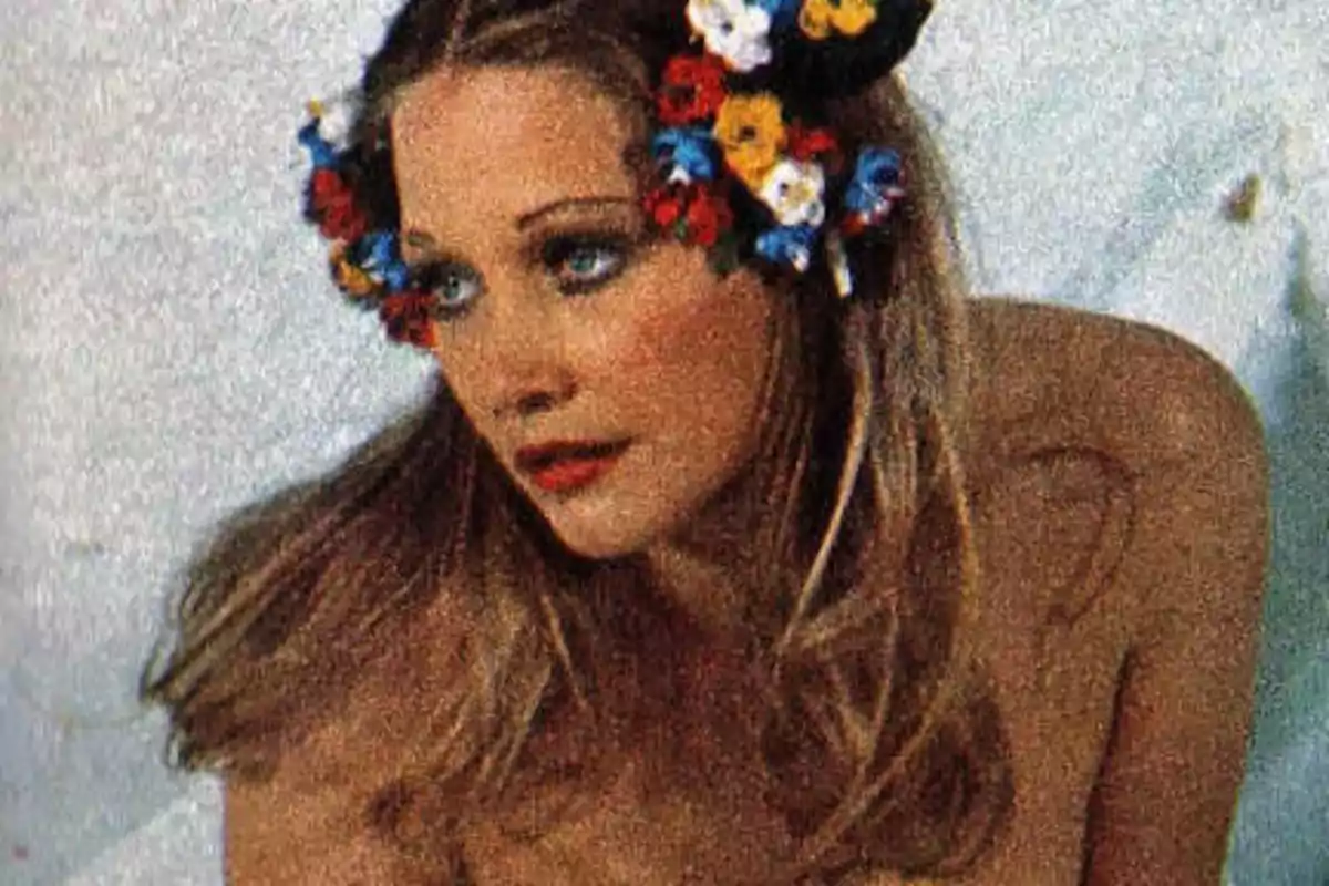 Mujer con corona de flores en el cabello y expresión pensativa.
