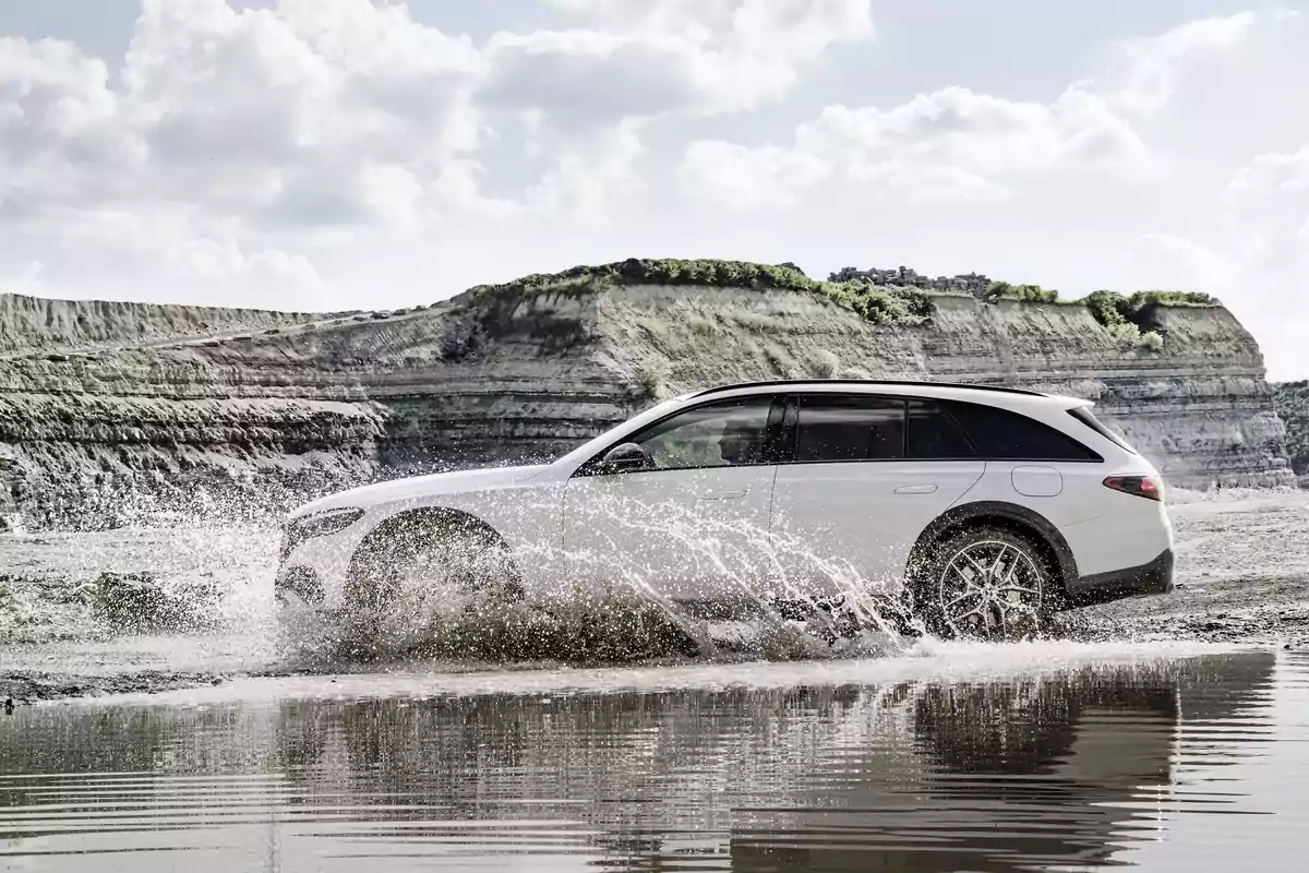 Un Mercedes-Benz E 300 de 4MATIC All-Terrain blanco cruza un charco en un paisaje rocoso. Un Mercedes-Benz E 300 de 4MATIC All-Terrain blanco cruza un charco en un paisaje rocoso.