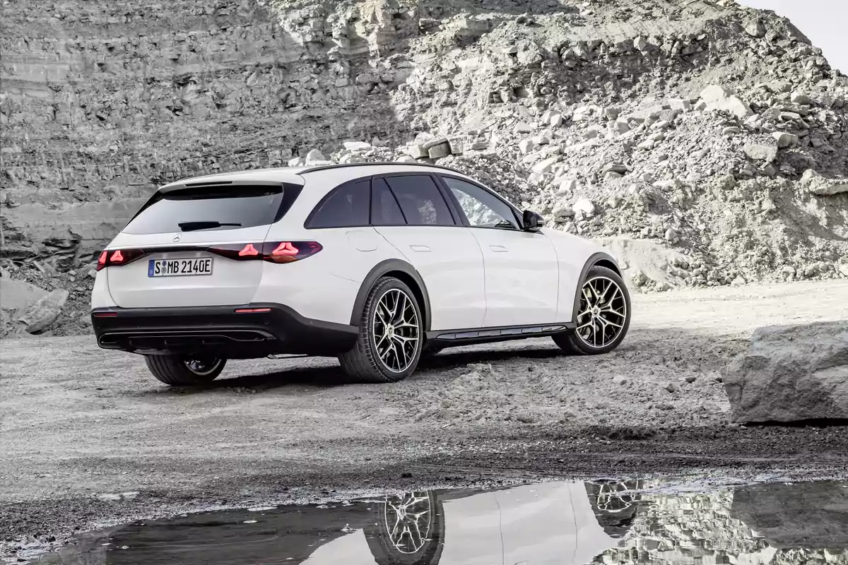 Un Mercedes-Benz E 300 de 4MATIC All-Terrain blanco estacionado en un terreno rocoso con un charco reflejando parte del vehículo. Un Mercedes-Benz E 300 de 4MATIC All-Terrain blanco estacionado en un terreno rocoso con un charco reflejando parte del vehículo.