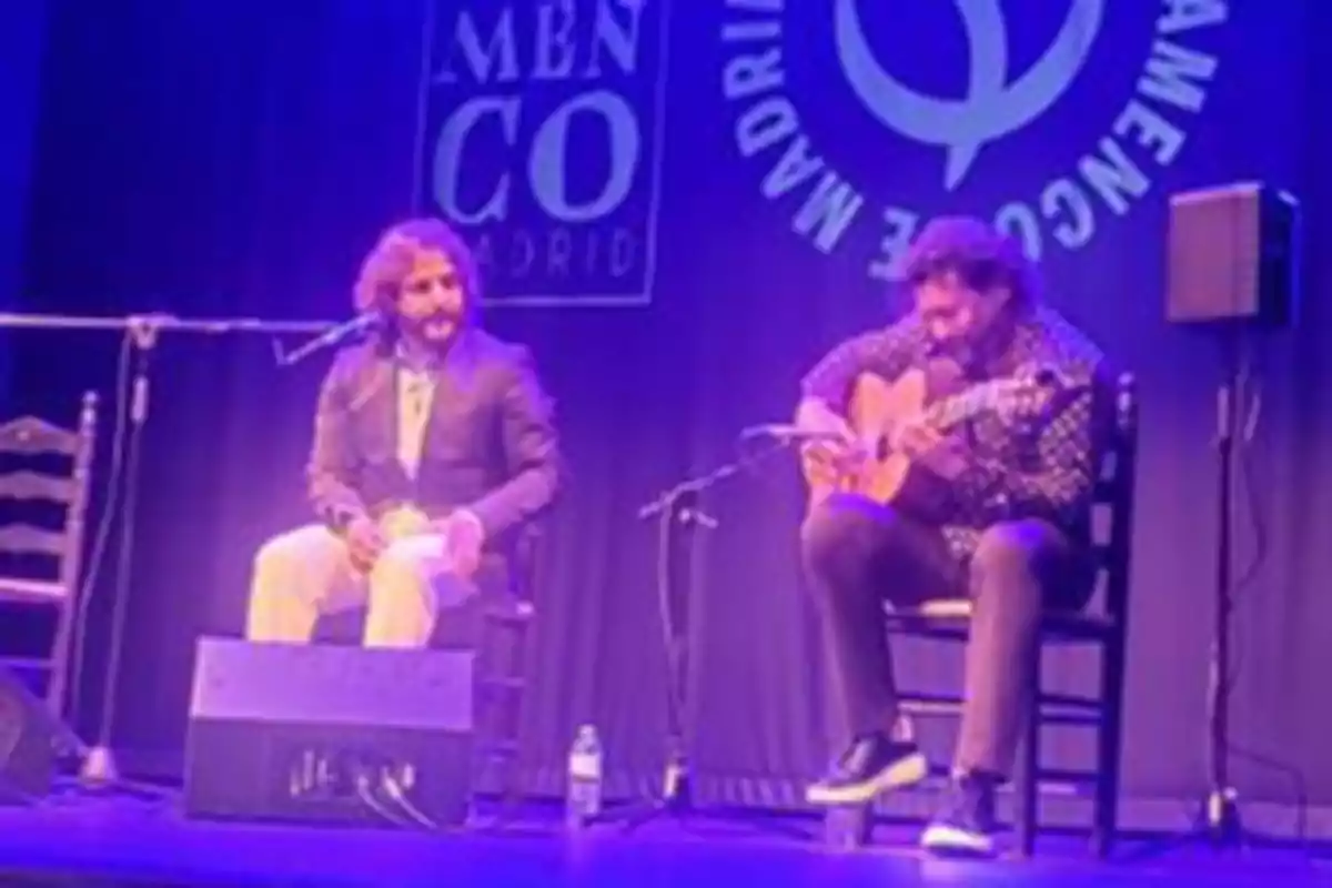 Dos músicos actuando en un escenario con el logo de "Flamenco Madrid" de fondo.