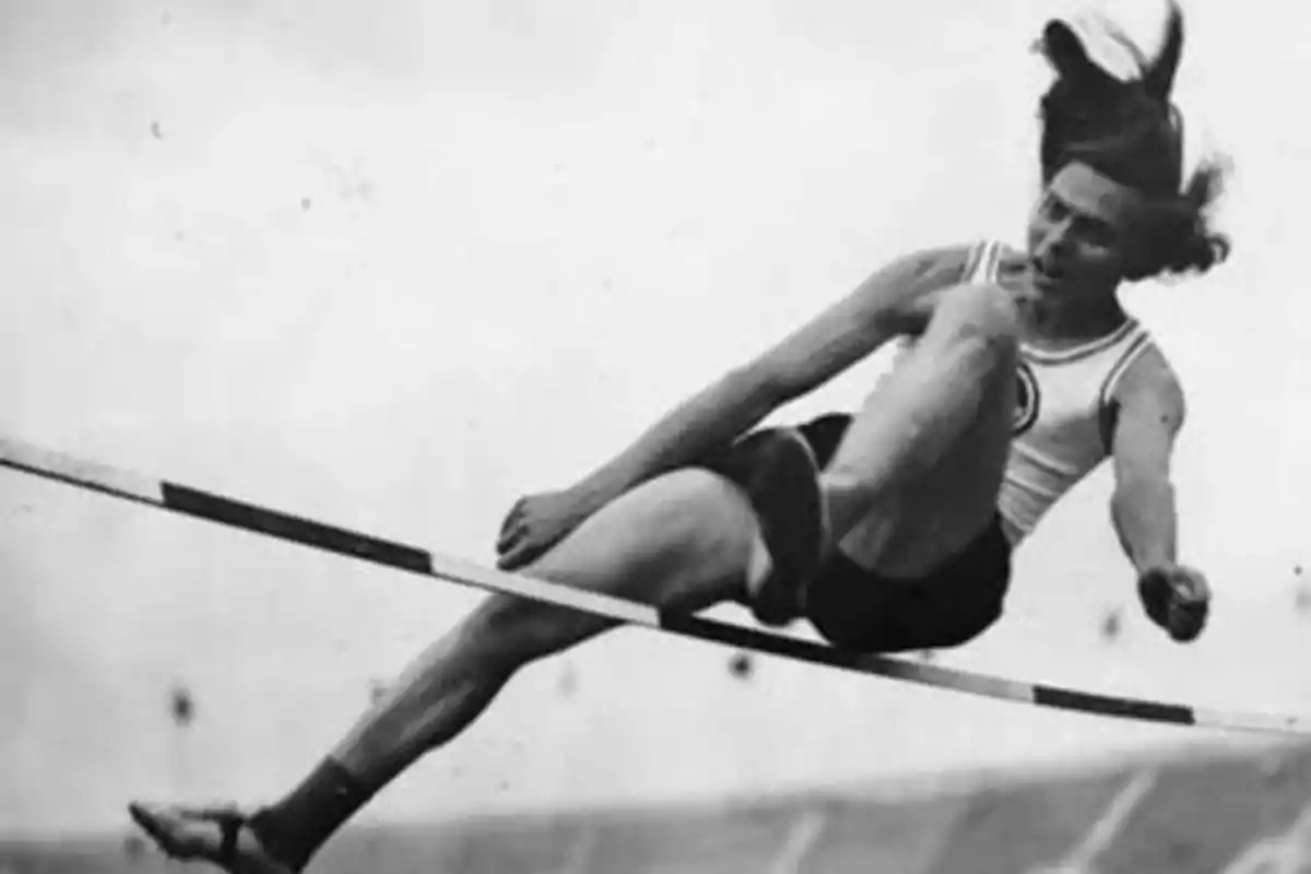 Atleta en blanco y negro realizando un salto de altura.