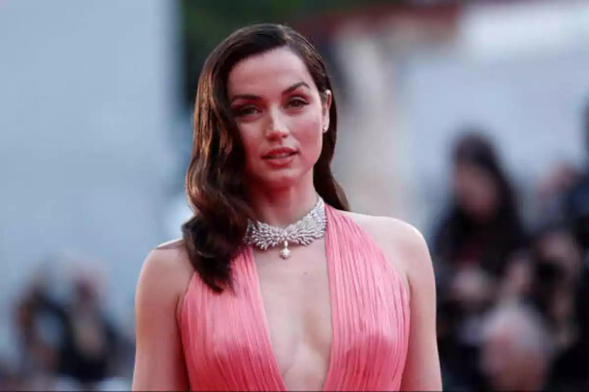 Mujer con vestido rosa y collar de perlas en un evento formal.