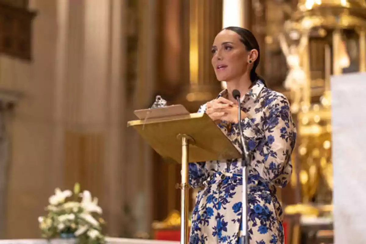 Una mujer hablando en un atril dorado dentro de una iglesia.