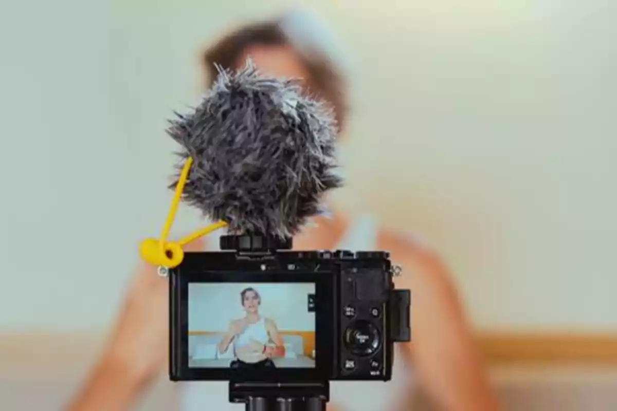 Persona grabando un video con una cámara equipada con un micrófono de peluche.