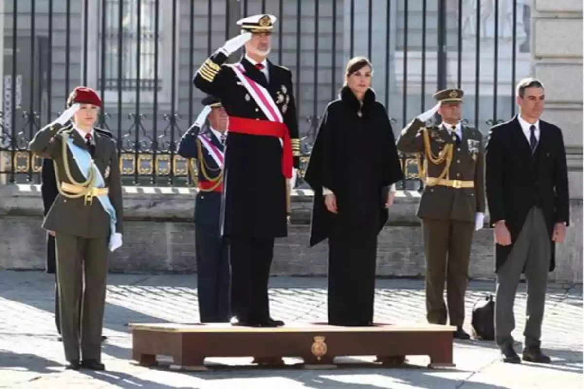 Personas en uniforme militar y formal rindiendo homenaje en una ceremonia oficial al aire libre.