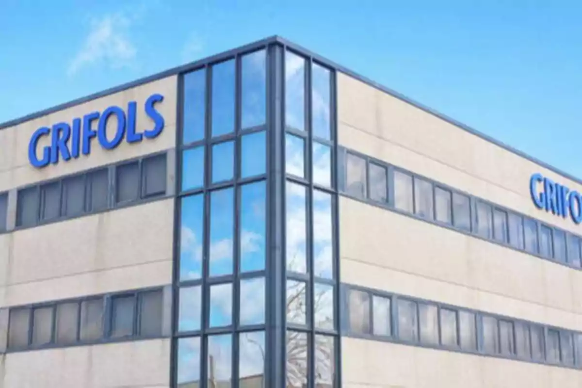 Edificio de oficinas de Grifols con fachada de vidrio y cielo azul reflejado.