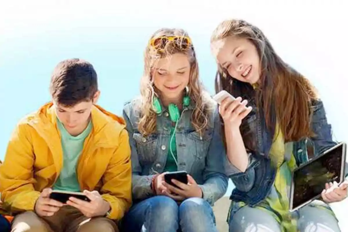 Tres jóvenes sentados usando dispositivos electrónicos.
