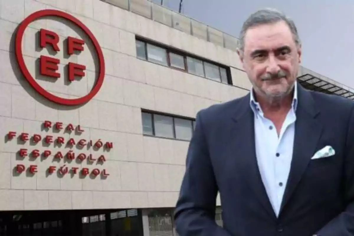 Un hombre de traje oscuro y camisa blanca está de pie frente a un edificio con el logotipo de la Real Federación Española de Fútbol (RFEF).