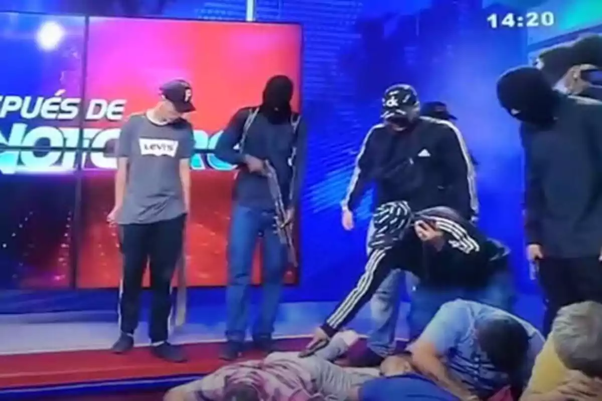 Un grupo de personas enmascaradas y armadas aparece en un set de televisión con varias personas en el suelo.