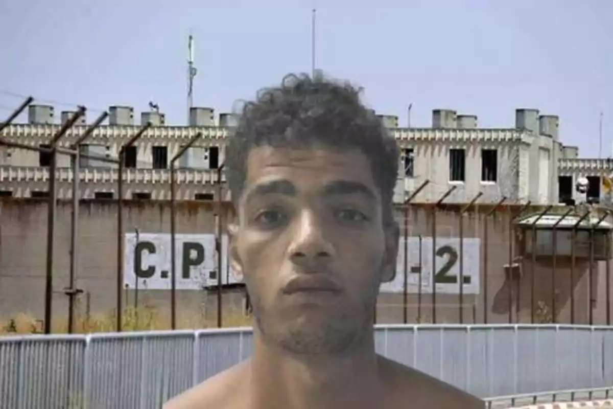 Hombre frente a una prisión con un cartel que dice "C.P. J. 2"