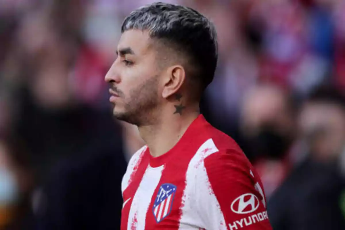 Jugador de fútbol con camiseta del Atlético de Madrid y tatuaje de estrellas en el cuello.