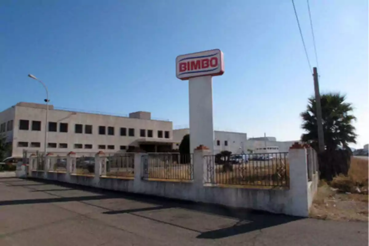 Fábrica de Bimbo con un letrero grande en la entrada y un edificio industrial al fondo.