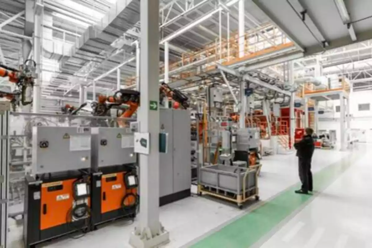Una fábrica moderna con maquinaria automatizada y un trabajador supervisando el proceso.