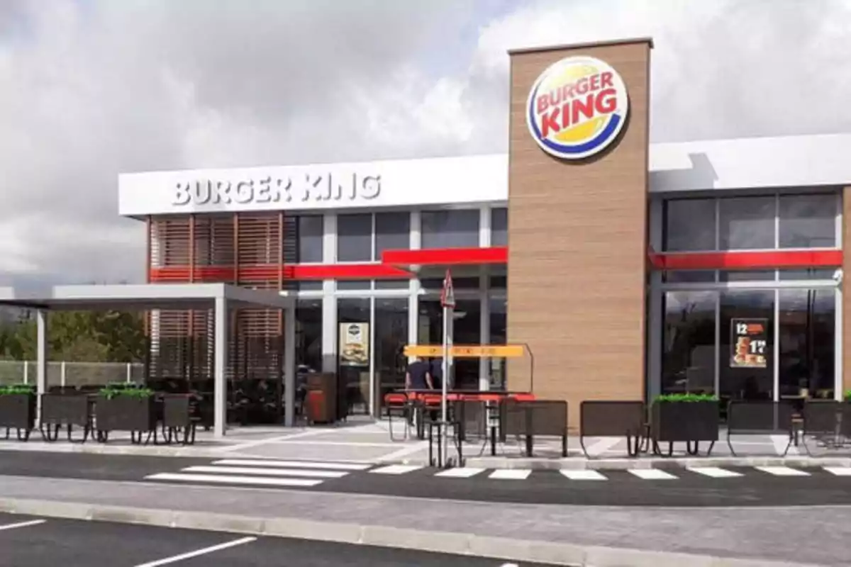 Fachada de un restaurante de Burger King con un área de comedor al aire libre y un estacionamiento en primer plano.