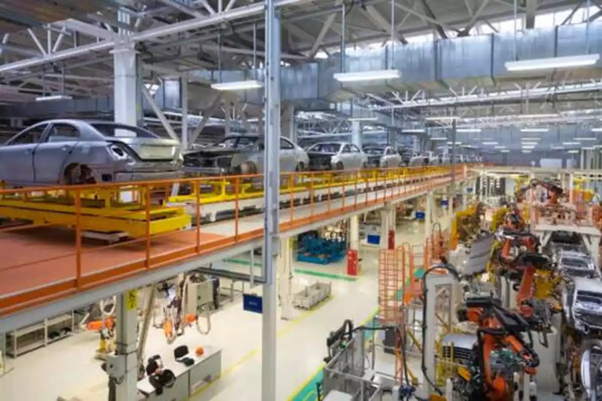 Línea de ensamblaje de automóviles en una fábrica moderna con robots industriales y carrocerías de autos en proceso de fabricación.